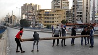 Para pengunjuk rasa membawa tiang kayu, saat mereka memblokir jalan raya utama yang mengarah ke bandara internasional Beirut, Senin, (29/11).