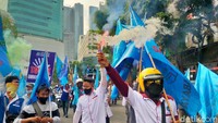 Massa buruh juga berjalan kaki dengan membawa spanduk dan menyalakan suar.