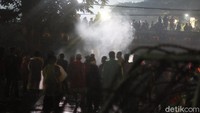 Asap putih mengepul dari sampah yang dibakar oleh massa buruh. Sementara itu, sejumlah peserta aksi sempat mendorong-dorong pagar berduri.