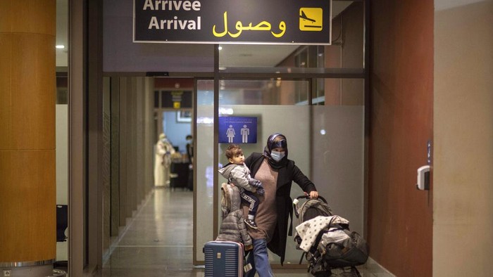 A man hugs his parents who are to travel on the last flight to Morocco before flights are suspended, arrives at a terminal in Rabat airport, Morocco, Monday, Nov. 29, 2021. Morocco announced it would suspend all incoming air travel from around the world starting Monday for two weeks because of the rapid spread of the new omicron variant, the government's committee in charge of monitoring COVID-19 announced Sunday. (AP Photo/Mosa'ab Elshamy)
