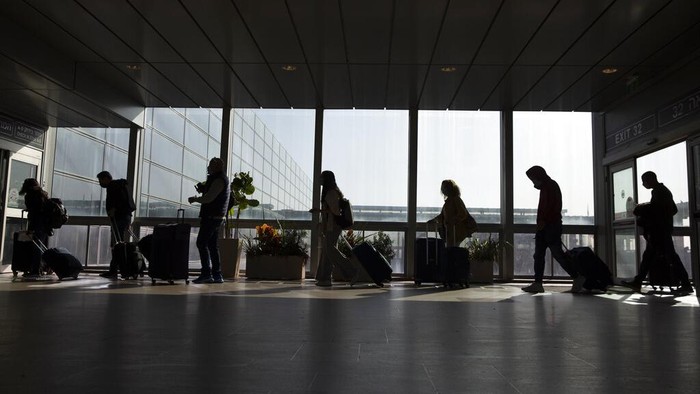Travelers walk with their luggage in the Ben Gurion Airport near Tel Aviv, Israel, Sunday, Nov. 28, 2021. Israel on Sunday approved barring entry to foreign nationals and the use of controversial technology for contact tracing as part of its efforts to clamp down on a new coronavirus variant. (AP Photo/Ariel Schalit)