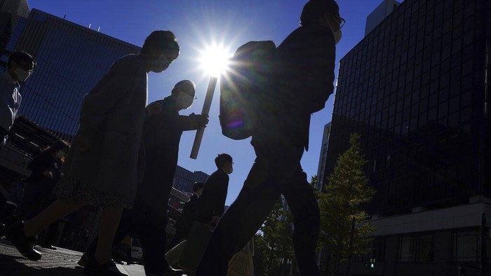 People wearing protective masks to help curb the spread of the coronavirus walk in a sunny day Thursday, Nov. 25, 2021, in Tokyo. (AP Photo/Eugene Hoshiko)