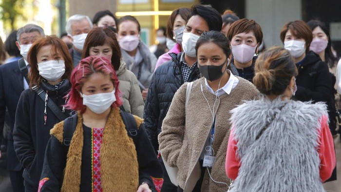 People wearing face masks to protect against the spread of the coronavirus walk along a street in Tokyo, Monday, Nov. 29, 2021. (AP Photo/Koji Sasahara)
