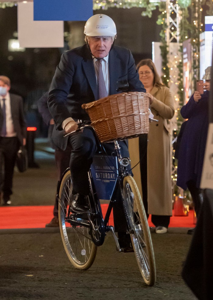 LONDON, ENGLAND - NOVEMBER 30: Britain's Prime Minister Boris Johnson rides a bike as he visits a UK Food and Drinks market set up in Downing Street on November 30, 2021 in London, England. (Photo by Justin Tallis - WPA Pool/Getty Images)
