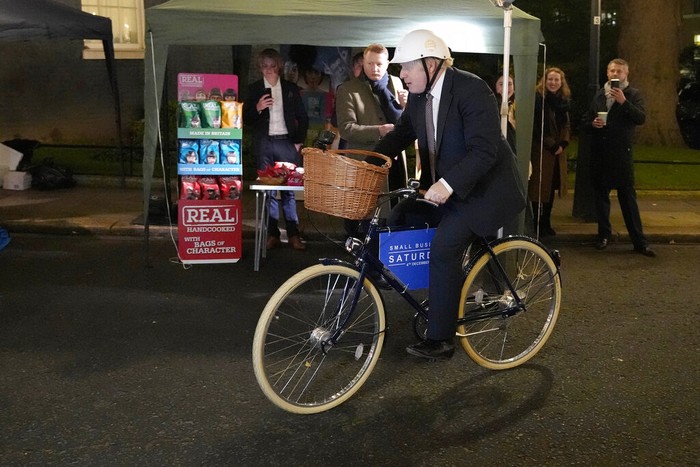 Britain's Prime Minister Boris Johnson puts on a helmet to ride a bicycle as he attends a UK Food and Drinks market set up in Downing Street in London, Tuesday, Nov. 30, 2021.(AP Photo/Frank Augstein)