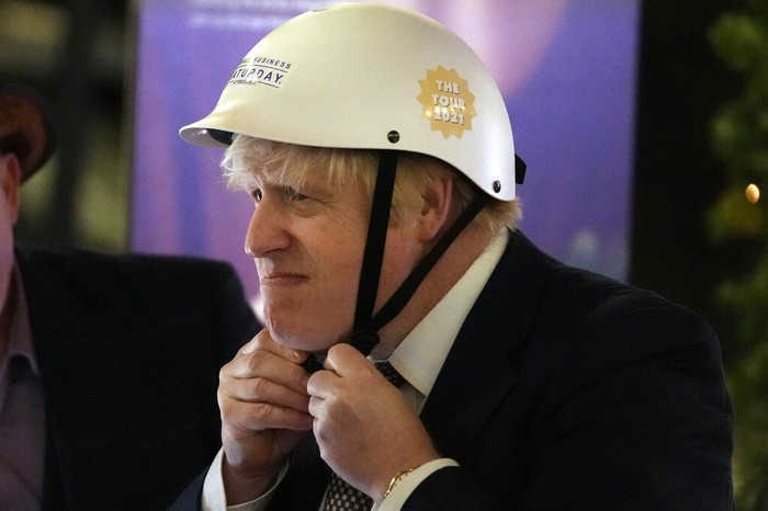 Britain's Prime Minister Boris Johnson puts on a helmet to ride a bicycle as he attends a UK Food and Drinks market set up in Downing Street in London, Tuesday, Nov. 30, 2021.(AP Photo/Frank Augstein)