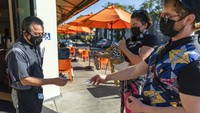 Tampak seorang petugas restoran memeriksa kartu vaksin milik warga yang hendak masuk ke salah satu tempat makan di kawasan Los Angeles, AS, Senin (29/11/2021). AP Photo/Damian Dovarganes. 