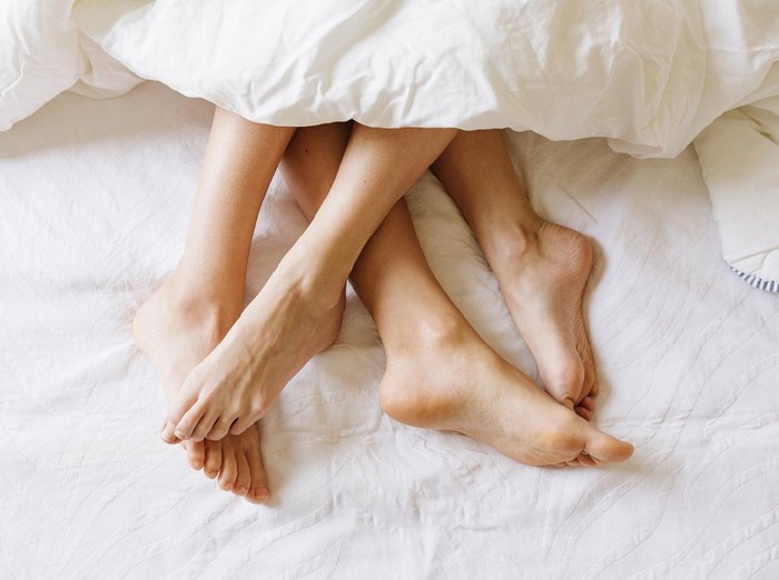 Close up of female feet in under the sheets.