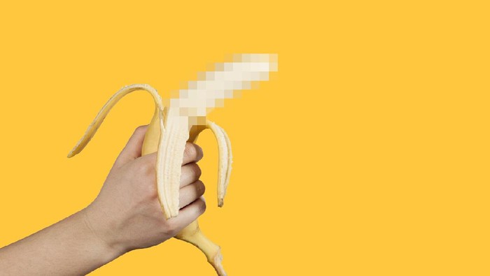 Banana as a symbol of male penis in hand on a yellow background hidden by censorship. Sexual masturbation and orgasm, impotence problem. Self-pleasure concept.