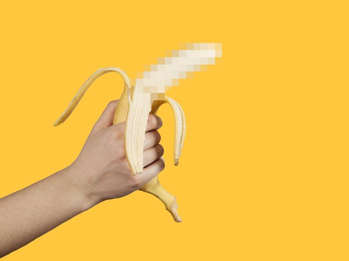 Banana as a symbol of male penis in hand on a yellow background hidden by censorship. Sexual masturbation and orgasm, impotence problem. Self-pleasure concept.