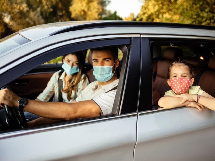 Family taking safety precautions to protect themselves while traveling with a car