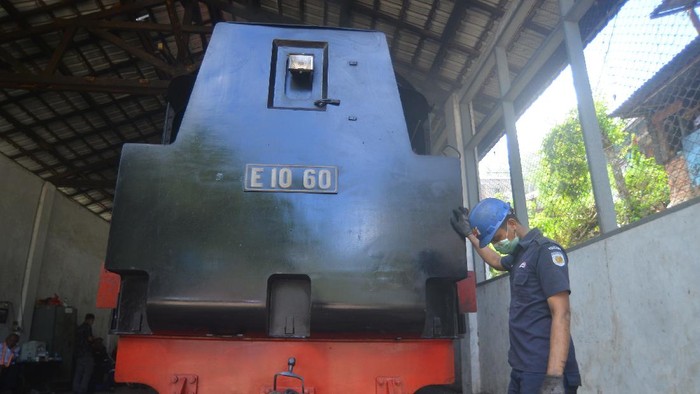 Pekerja memasok batu bara untuk menyalakan lokomotif uap E 1060 