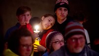 Allison Hepp, 15, memegang lilin sambil bersandar pada saudara laki-lakinya Benjamin Hepp, 17, saat keduanya berdiri di samping teman-teman sekelas mereka selama doa doa setelah penembakan di sekolah Oxford High School. (AP/Jake May)