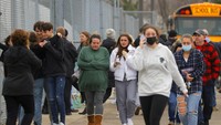Orang tua berjalan pergi dengan anak-anak mereka dari tempat parkir Meijer di Oxford di mana banyak siswa berkumpul menyusul situasi penembak aktif di Oxford High School. (AP/Eric Seals)