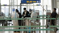 Anggota staf yang mengenakan alat pelindung memandu penumpang di Bandara Internasional Incheon Di Incheon, Korea Selatan. Dua kasus diduga varian Omicron ini ditemukan saat negara ini memperketat pembatasan masuk untuk orang-orang dari negara-negara Afrika demi mencegah varian baru itu. AP/Ahn Young-joon