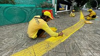 Sejumlah petugas dikerahkan untuk mengecat ulang jalur kunin atau yang dikenal dengan sebutan guiding block di trotoar Jalan Bulungan Raya, Blok M, Jakarta Selatan, Rabu (01/12/2021).