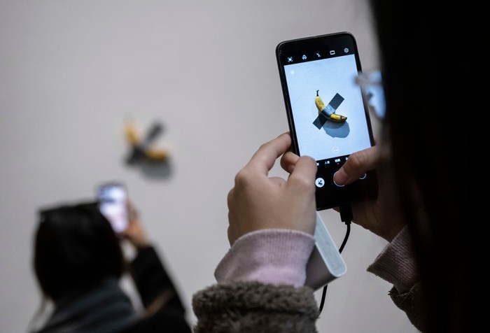 Wuih! Karya Seni Pisang Dilakban Mejeng Lagi, Diserbu Warga Beijing BEIJING, CHINA - NOVEMBER 28: Visitors take pictures of the work