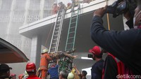 Korban diturunkan dari lantai atas gedung dengan menggunakan tandu dan tangga.