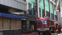 Tampak petugas pemadam tengah melakukan evakuasi terhadap 2 karyawan gedung yang sempat terjebak didalam gedung.  