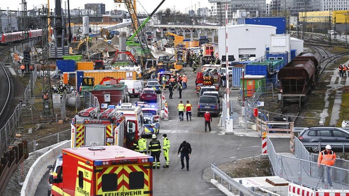 Germany Explosion Firefighters go to an S-Bahn together with railway staff at a railway site in Munich, Germany, Wednesday, Dec. 1, 2021. Police in Germany say three people have been injured including seriously in an explosion at a construction site next to a busy railway line in Munich. (Sven Hoppe/dpa via AP)
