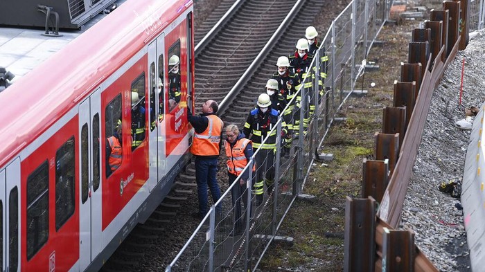 Germany Explosion Firefighters go to an S-Bahn together with railway staff at a railway site in Munich, Germany, Wednesday, Dec. 1, 2021. Police in Germany say three people have been injured including seriously in an explosion at a construction site next to a busy railway line in Munich. (Sven Hoppe/dpa via AP)