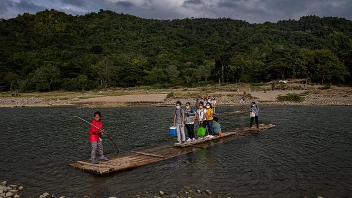 ARINGAY, PHILIPPINES - DECEMBER 01: Healthcare workers cross a river as they transport COVID-19 vaccines to rural villages on December 01, 2021 in Aringay, La Union province, Philippines. The Philippines is rushing to vaccinate its population as it mulls making COVID-19 vaccination mandatory and amid the looming threat of the Omicron variant of the coronavirus. The country, which has just approved booster shots for its adult population, launched a three-day national vaccination holiday on November 29 to December 1 with the goal of vaccinating at least nine million additional people. (Photo by Ezra Acayan/Getty Images)