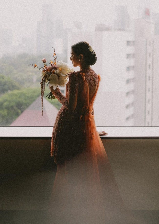 Sheila Dara tampil anggun dengan kebaya oranye rancangan Svarna by Ikat Indonesia yang digawangi desainer Didiet Maulana. Kebaya tampak mewah dengan detail lace, bordir serta ekor panjang. Foto: Instagram