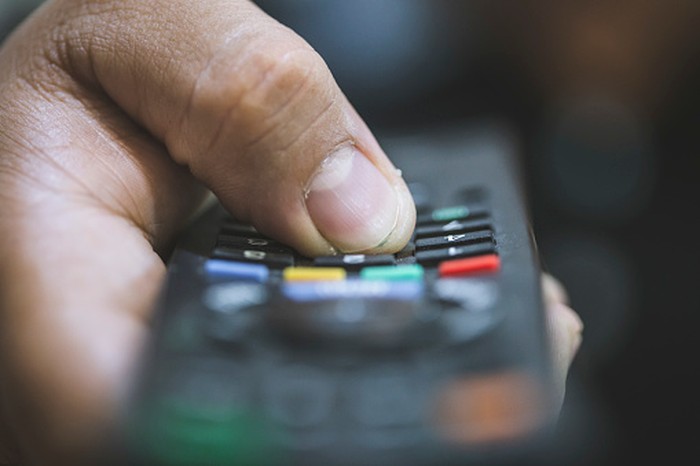 Close-up of a remote control sitting on a couch in an empty modern living room.