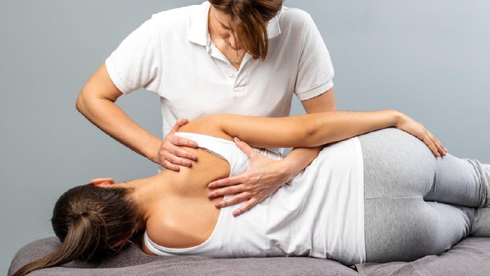698127146 Close up of female osteopath doing shoulder blade therapy on young woman.