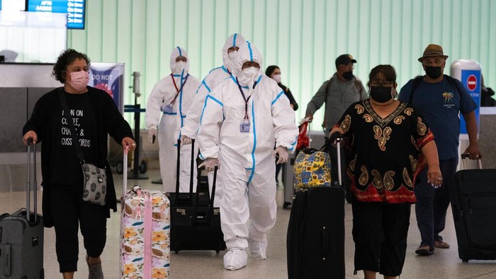 Sejumlah pelancong kenakan APD lengkap saat tiba di Bandara Internasional Los Angeles, AS. Hal itu dilakukan usai munculnya varian Omicron yang gegerkan dunia.