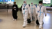 Sejumlah pegawai maskapai Air China mengenakan APD lengkap saat tiba di Bandara Internasional Los Angeles, Amerika Serikat.