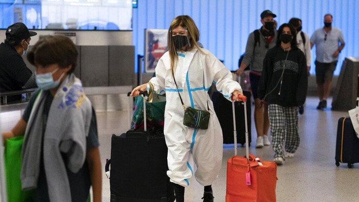 Potret Pelancong AS Pakai APD Lengkap, Ngeri Ketularan Varian Omicron Sejumlah pelancong kenakan APD lengkap saat tiba di Bandara Internasional Los Angeles, AS. Hal itu dilakukan usai munculnya varian Omicron yang gegerkan dunia.