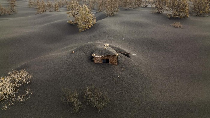 Potret Pemukiman yang Terkubur Abu Gunung Berapi di Spanyol A soccer field is covered with ash from the volcano on the Canary island of La Palma, Spain, Wednesday, Dec. 1, 2021. A fresh stream of lava from volcano on Spain's La Palma threatened on Wednesday to engulf a parish church that has so far survived the eruption that shows no signs of relenting in its tenth week. (AP Photo/Emilio Morenatti)