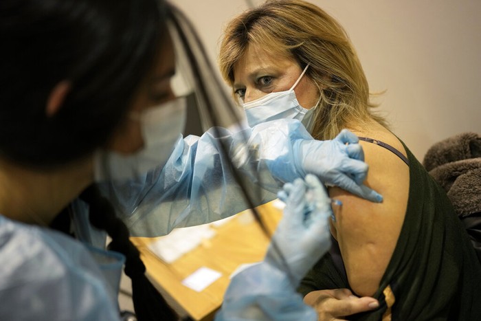 Virus Outbreak Portugal Nurse Carolina administers a booster shot of the Pfizer vaccine against COVID-19 to a fellow nurse on the first day of a new vaccination center in Lisbon, Wednesday, Dec. 1, 2021. Long lines formed at the Portuguese capital's largest vaccination center to date as authorities there tried to encourage the 2% of the population who are not vaccinated yet, Europe's lowest rate, and to speed up the administration of booster shots. (AP Photo/Armando Franca)