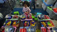 Seorang anak tampak asyik main masak-masak.