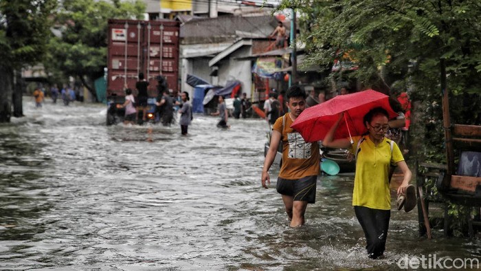 Warga mengatur lalu lintas di kawasan jalan yang terendam air rob, Jalan Lodan, Ancol, Jakarta Utara, Sabtu (4/12). Jalan Lodan, Ancol, menjadi lumpuh karena banjir air rob.
