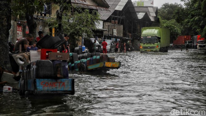 Warga mengatur lalu lintas di kawasan jalan yang terendam air rob, Jalan Lodan, Ancol, Jakarta Utara, Sabtu (4/12). Jalan Lodan, Ancol, menjadi lumpuh karena banjir air rob.