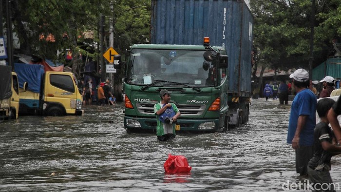 Warga mengatur lalu lintas di kawasan jalan yang terendam air rob, Jalan Lodan, Ancol, Jakarta Utara, Sabtu (4/12). Jalan Lodan, Ancol, menjadi lumpuh karena banjir air rob.