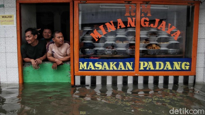 Sejumlah pedagang dan pekerja melintasi kawasan yang terendam air rob di Lodan Ancol, Jakarta Utara, Sabtu (4/12). Pantauan di lapangan terlihat sejumlah pedagang tetap berjualan mencari nafkah.