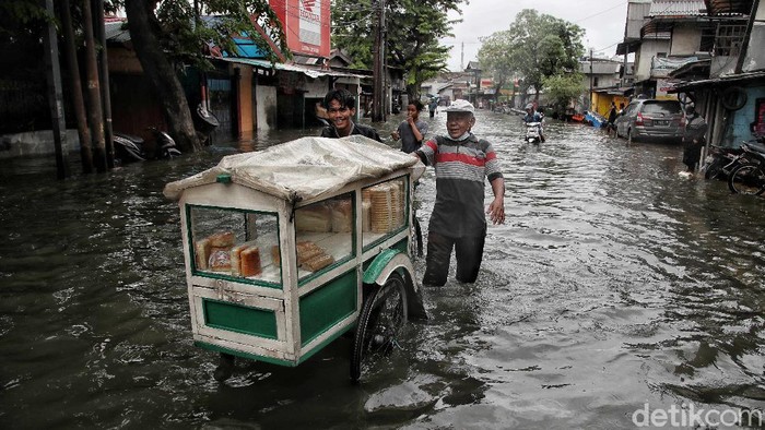 Sejumlah pedagang dan pekerja melintasi kawasan yang terendam air rob di Lodan Ancol, Jakarta Utara, Sabtu (4/12). Pantauan di lapangan terlihat sejumlah pedagang tetap berjualan mencari nafkah.