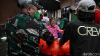 Warga menggunakan perahu karet saat evakuasi.