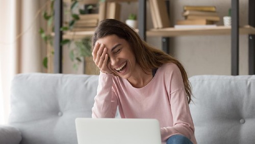 Laughing woman sitting on sofa watch comedy movie on pc enjoy funny videos stand up show online program listens comic feels overjoyed, weekend activities at home, wireless tech internet usage concept