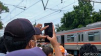 Beberapa warga mengeluarkan HP untuk memotret perbaikan KRL anjlok.