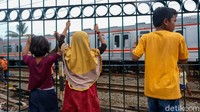 Anak-anak tampak memanjat pagar pinggir rel.