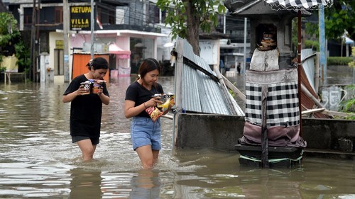 Warga duduk di atas mobil yang tergenang banjir di kawasan Legian, Kuta, Badung, Bali, Senin (6/12/2021). Hujan deras yang mengguyur wilayah Bali sejak Minggu (5/12) mengakibatkan banjir di sejumlah titik di kawasan Kuta dengan ketinggian air yang bervariasi. ANTARA FOTO/Fikri Yusuf/aww.
