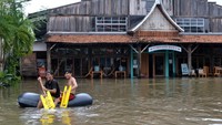 Beberapa warga menggunakan kasur angin untuk menerobos banjir.