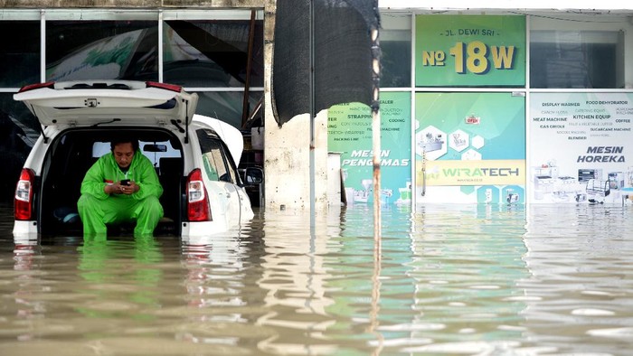 BANJIR DI KUTA BALI Warga duduk di atas mobil yang tergenang banjir di kawasan Legian, Kuta, Badung, Bali, Senin (6/12/2021). Hujan deras yang mengguyur wilayah Bali sejak Minggu (5/12) mengakibatkan banjir di sejumlah titik di kawasan Kuta dengan ketinggian air yang bervariasi. ANTARA FOTO/Fikri Yusuf/aww.