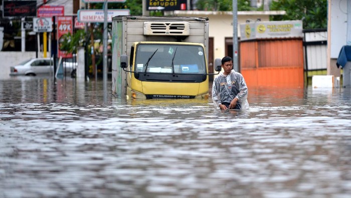 Warga duduk di atas mobil yang tergenang banjir di kawasan Legian, Kuta, Badung, Bali, Senin (6/12/2021). Hujan deras yang mengguyur wilayah Bali sejak Minggu (5/12) mengakibatkan banjir di sejumlah titik di kawasan Kuta dengan ketinggian air yang bervariasi. ANTARA FOTO/Fikri Yusuf/aww.