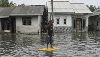 Seorang anak bermain saat banjir rob menggenangi Desa Pantai Mekar, Muaragembong, Kabupaten Bekasi, Jawa Barat, Senin (6/12).
