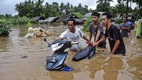 Sejumlah warga mendorong sepeda motornya melewati banjir di Dusun Kebon Lauk, Desa Sesela, Kecamatan Gunungsari, Lombok Barat, NTB. Banjir yang terjadi karena hujan lebat dan luapan air Sungai Meninting di wilayah Gunungsari tersebut mengakibatkan ratusan rumah warga terendam.